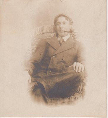 Postcard of man sitting in a wicker chair, possibly studio portrait