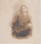 Postcard of man sitting in a wicker chair, possibly studio portrait