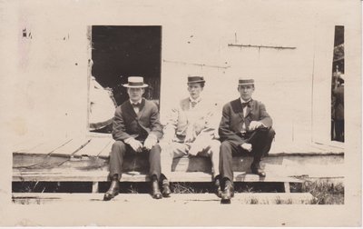 Postcard of three men sitting on a porch