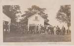 Postcard of a group of men outside a house