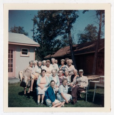 Photograph of Marjorie Rutherford, Gertie Velleau, Len Bradford, Margaret Mackie, Mrs. Harvey, Goldie Cox, Grace Corbyn, Leitha Evely, Maggie Mackie, Mrs. Roy Packard, Flossie Pebbles, Grace MacGregor, Gladys Hart, Ida Pebbles, Gert Bradford, Amy Gresham, Ellen MacGregor and Kate Thompson, Colborne Women's Institute Scrapbook