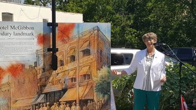 Town Councillor Jane Fogel speech - gestures towards utility box cover with image of the McGibbon Hotel.