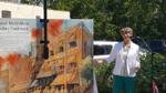 Town Councillor Jane Fogel speech - gestures towards utility box cover with image of the McGibbon Hotel.