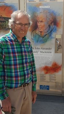 Sandy Mackenzie stands in front of the panel about him on the utility box cover.