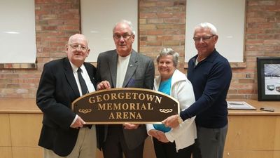 Members of the Sports Museum holding a sign commemorating the Georgetown Memorial Arena.