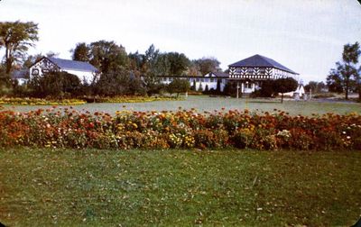 A view of the Dominion Seed House with beds of blooming flowers  in the foreground.