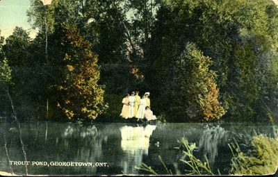Five ladies and a girl gather with a man at the  shore of the Lawson’s Trout Pond.