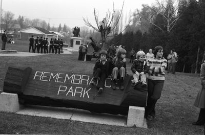 Children sit on the Remembrance Park sign to watch the parade