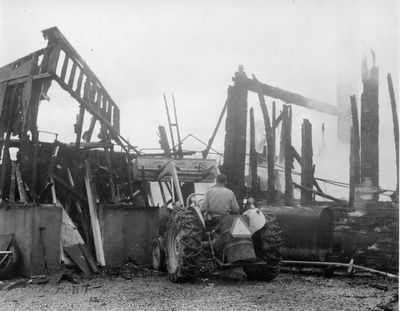 A front end loader knocks down the burnt remains of Norval Garage