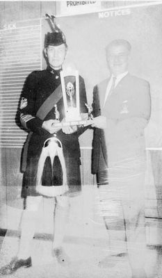 A Lorne Scot in full Highland garb receives a trophy in the Legion