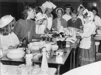 Brownies in costumes of the 1800s gather around a bazaar table