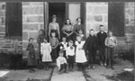 Children and three women in front of Stone School at Henderson's Corners.
