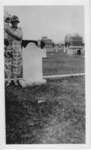 Unidentified woman and child standing at a gravestone in a cemetery