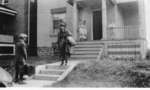 Unidentified couple standing in front of house with luggage in hand