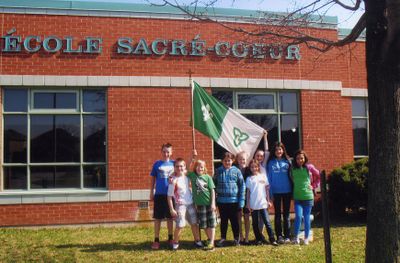 Enfants devant L'École Sacré-Cœur avec drapeau franco-ontarien