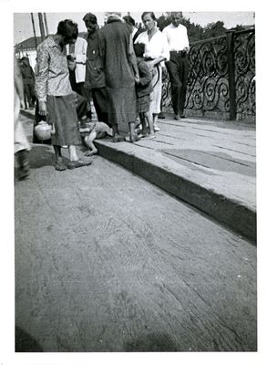 Small group of people gathered around a child lying dead near the edge of a sidewalk in Kharkiv