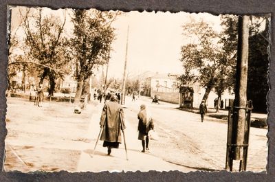 A woman on crutches and a young girl walk down a residential street in Kharkiv