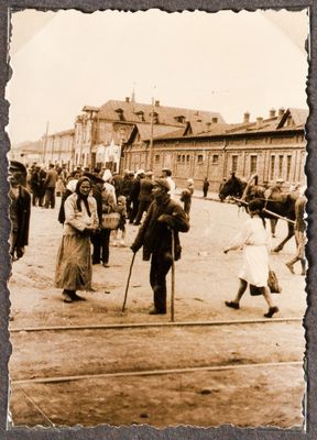 Many people milling about on a broad city street or square in Kharkiv, with a man leaning on crutches and two women in the foreground