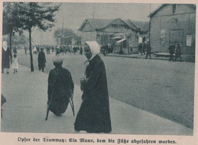 Street scene in Kharkiv with a woman and a man on crutches in the foreground and a crowd of people in the background