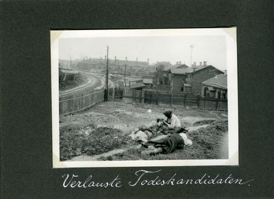 Three women resting on a grassy plot near some houses and a factory in Kharkiv