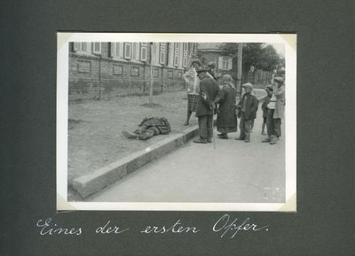 Small group of people gathers around a famine victim lying dead on a sidewalk in Kharkiv