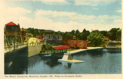 View of the Muskoka River in Huntsville, Ontario: the swing bridge, waterfront, town dock, Main Street,  J.R. Boyd and Son store, steamboat Algonquin at far right.