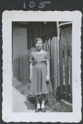 Unidentified Young Girl Standing in front of a Fence