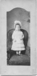 Portrait of an unidentified young girl dressed formally and standing on a chair.