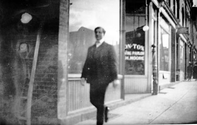 Man walking past stores on Main St., Milton.