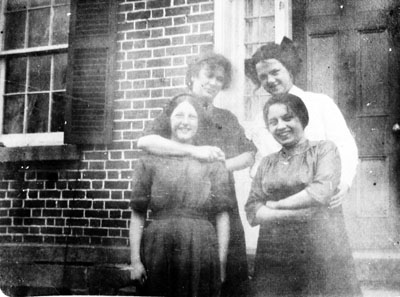 Four women posed in front of door