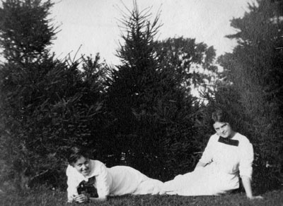 Two women in white dresses seated on ground