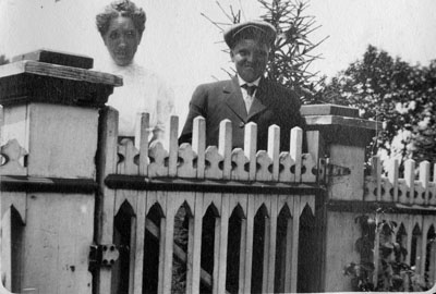 Man and woman posed behind white gate