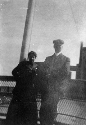 Man and young lady posed on rail of ship