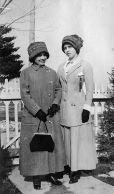 Two young ladies standing against fence