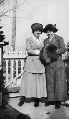 Two young ladies posed against fence