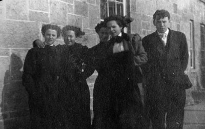 Four women and one man posed outside stone building