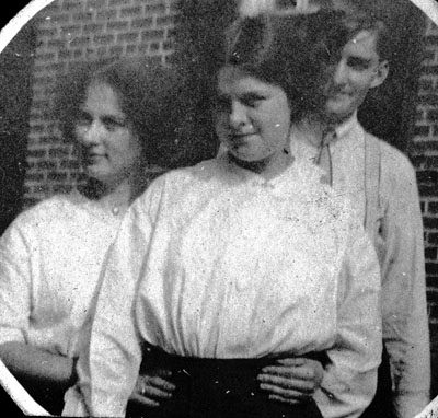 Man, woman and young lady posed by brick wall