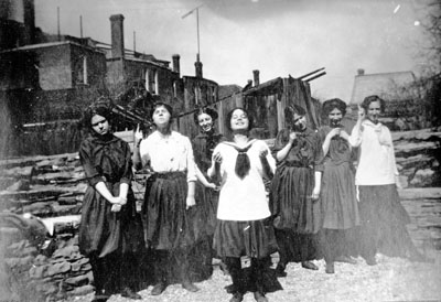 Seven young ladies standing in front of stone wall