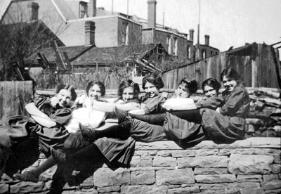 Seven young ladies seated on stone wall