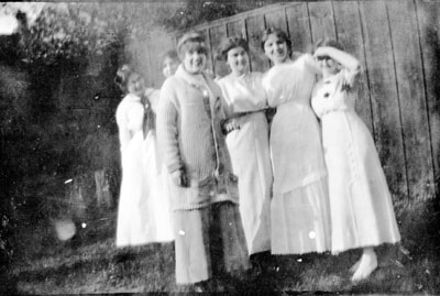 Seven women posed by fence