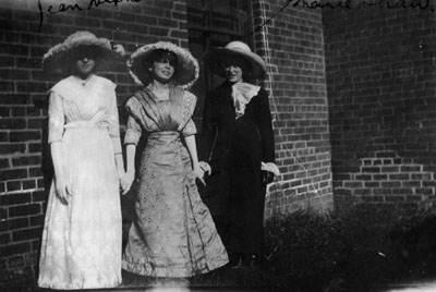 Three young women posed by brick wall