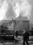 Two men posed with houses in background