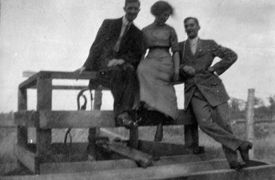 Two men and a woman sitting on railing