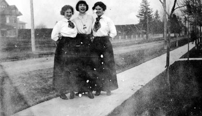 Three young ladies standing on sidewalk