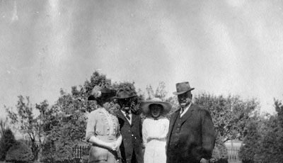 Elderly man, middle-aged couple and young lady posed against trees