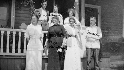 Five women and two men posed by porch