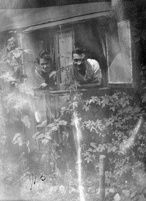 Man and woman leaning through cottage window