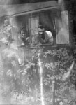 Man and woman leaning through cottage window