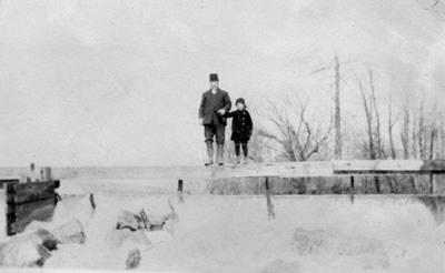 Man and girl on top board of mill pond spillway.