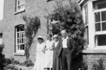 Four people standing in front of house.